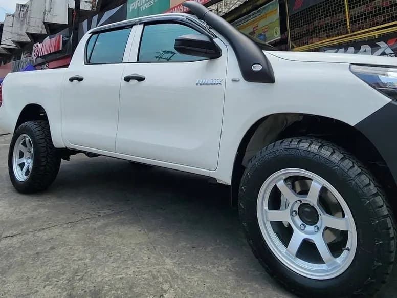 White Toyota Hilux on silver all-terrain mags
