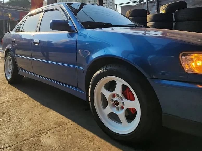 Blue sedan on white racing mags with tires stacked behind