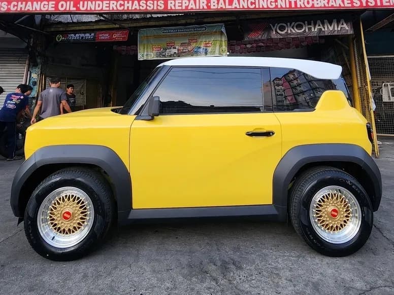 Yellow city car on gold BBS-style mags in front of the shop